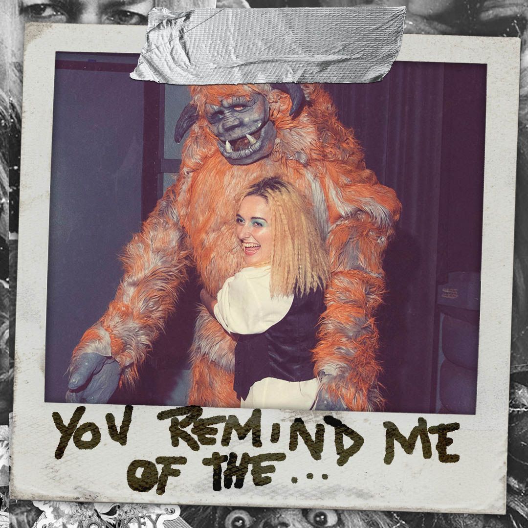 A woman dress as David Bowie's character in labyrinth hugs a big, friendly and orange monster called Ludo 